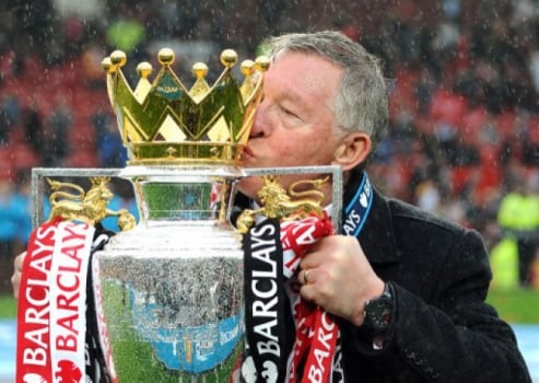 Sir Alex Ferguson dá um beijo na taça da Premier League conquistada pelo Manchester United em 2013, seu último título