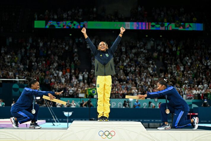 Rebeca Andrade sendo referenciada pelas estadunidenses Jordan Chiles e Simone Biles