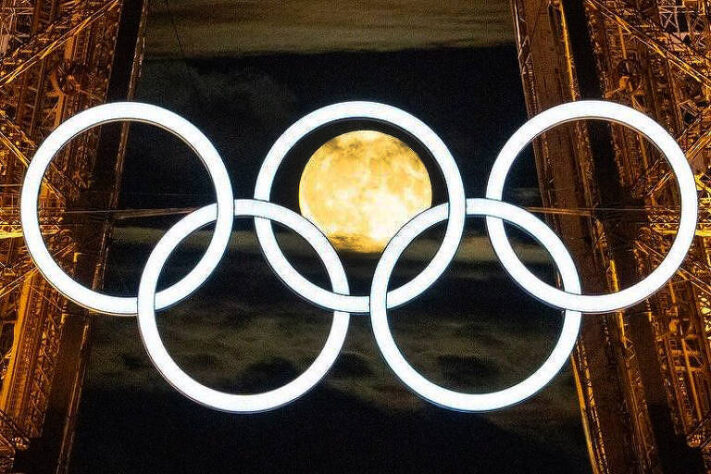 A lua no meio dos arcos olímpicos da Torre Eiffel