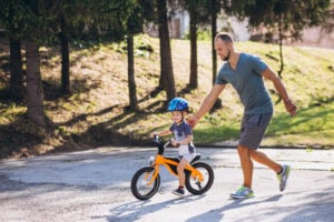 Pai ensinando o filho a andar de bicicleta.